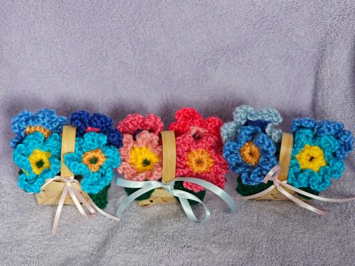crochet flowers in bamboo baskets, blue and pink with dark green crochet leaves
